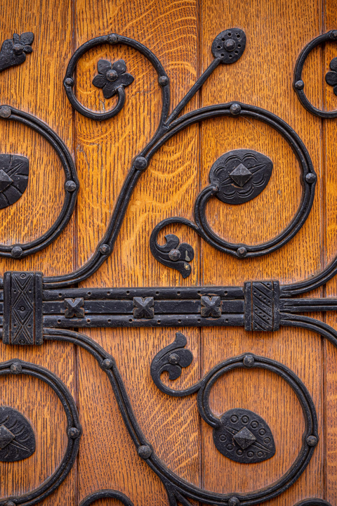 Detail show of swirling wrought iron vines adorning a wooden door
