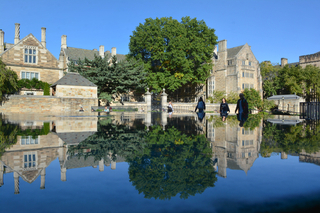 the sky and Yale’s buildings reflected in a pool of water