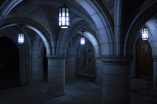 Shadowy and dramatically low lit stone archways of the Humanities Quadrangle at night