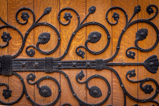 Detail show of swirling wrought iron vines adorning a wooden door
